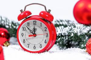 Bokeh Photo of Red Alarm Clock showing almost 12 in Christmas Theme