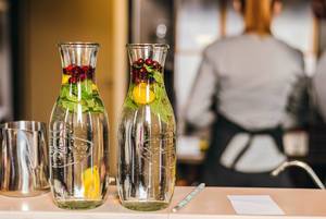 Bokeh Photo of two Water Carafe with Fresh Cranberry Lemon Fruit Water with Bartender in the Background