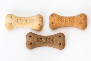 Bone-shaped dog treats in three different colours on white background