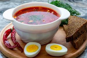 Bowl of beetroot soup borsch with egg, pepper and slices of black bread