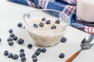 Breakfast background with oatmeal and blueberries and yogurt in glass