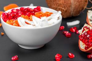 Breakfast background with oatmeal, coconut, pomegranate seeds and dried apricots in a white bowl (Flip 2020)