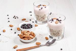 Breakfast concept. Oatmeal with almonds, yogurt and black elderberry