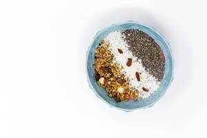 Breakfast - Granola nut crunchy cluster cereals with coconut flakes, chia seeds and goji berries in a bowl - Top view