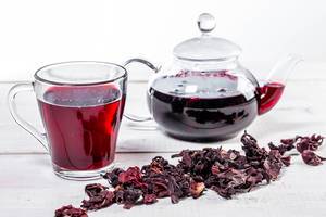 Brewed hibiscus tea in a glass teapot and a Cup with dry hibiscus flowers (Flip 2019)