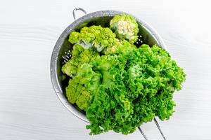 Broccoli and lettuce with water drops in a sieve. Top view (Flip 2019)