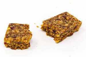 Broken cereal bar and crumbles by Hafervoll Flapjack with Mexican flavor, shot on white surface