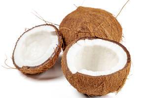 Broken fresh coconut halves and whole coconut on a white background