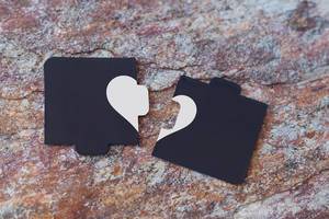 Broken heart made of two pieces of jigsaw puzzle on the marble. Broken heart, loneliness, divorce and unhappy relationships concepts (Flip 2020)