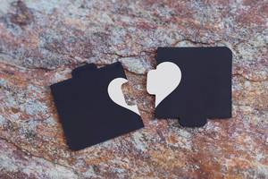 Broken heart made of two pieces of jigsaw puzzle on the marble. Broken heart, loneliness, divorce and unhappy relationships concepts