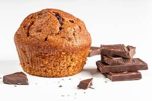 Brown muffin with chocolate pieces on white background