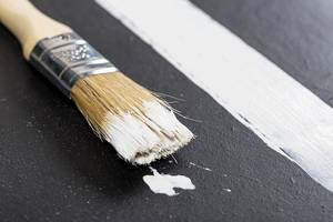 Brush and strip of white paint on black background