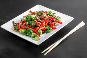 Brussels sprouts, sliced mushrooms and bell peppers with sesame seeds on a black background