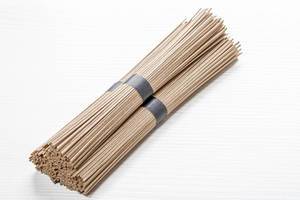 Bundles of raw buckwheat soba noodles on white wooden background (Flip 2019)