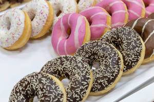 Bunte Donuts mit weißer und pinker Glasur, mit Schokoguss und bunten Streuseln