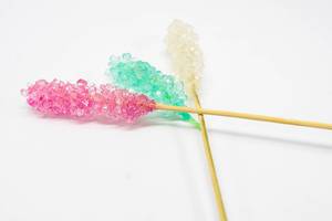 Bunte, leuchtende Süßigkeiten-Spieße aus Kandiszucker, auf weißem Untergrund
