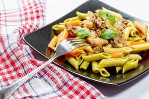 Bunte pasta an Pilzen und Fleisch mit einer Gabel