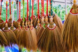Bunte Reisig-Besenstiele hängen zum Verkauf von der Decke eines lokalen Marktstands