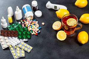 Bunte Tabletten und Medizin und heißer Zitronentee als Symbolik für moderne und traditionelle Heilmethoden