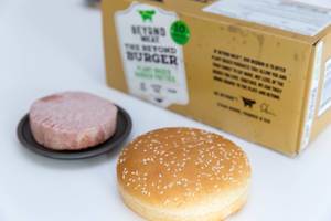 Burgerbrötchen in Nahaufnahme mit Beyond Meat pflanzlicher, sojafreier und glutenfreier Burger-Pastetchen auf schwarzem Teller
