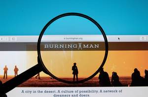 Burning Man logo on a computer screen with a magnifying glass
