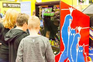 Burschen spielen Space Invaders auf einem Arcade-Automaten - Gamescom 2017, Köln
