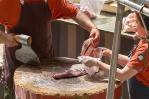Butcher cuts lamb legs with an axe