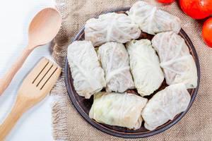 Cabbage rolls with meat and rice on burlap with wooden spoon and fork