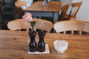 Cafe interior. Coffee table with rose in vase and sugar table