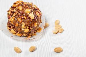 Cake with cocoa and roasted peanuts on a white wooden background