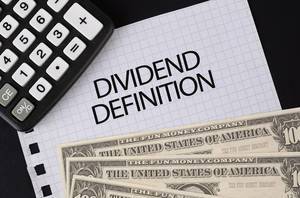 Calculator, money and Dividend Definition text on black table