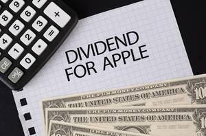 Calculator, money and Dividend For Apple text on black table
