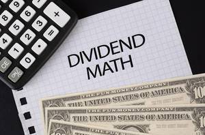 Calculator, money and Dividend Math text on black table