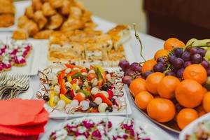 Canapés, gesunder Frühstückstisch mit Obst, Weintrauben, Orangen und Kuchen