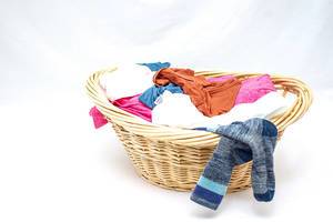 Cane Laundry Basket with Clothes and Socks hanging on it on white Background