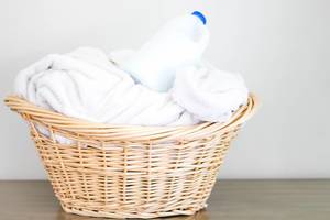 Cane Laundry Basket with White Towels and a Bottle of Detergent on Top