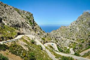 Car Driving down Serpentine Mountain Road with Blue Sky and Sea View in Palma de Mallorca