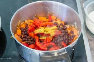 Caribbean sweet potatoe stew with coconut milk, black beans and red bellpeppers in a pot on the stove
