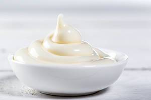 Ceramic white gravy boat with mayonnaise on white background