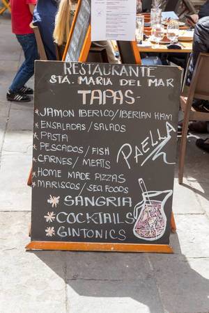 Chalkboard menu recommendation of the Santa Maria del Mar restaurant including Spanish specialties such as Iberian ham, tapas, paella and sangria on a street in Barcelona