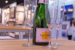 Champagnerflasche Veuve Clicquot mit drei leeren Champagnergläsern auf Holztisch