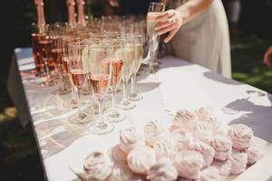 Champagnergläser und rosa Zephyrs-Baiser auf einem festlichen Tisch im Garten