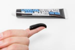 Charcoal coconut-toothpaste on a finger for display