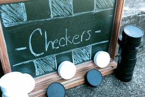 Checkers written on chalkboard and tokens around it
