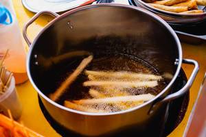 Cheesesticks being deep fried inside a hot pot