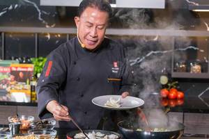 Chef Martin Yan cooks crab chips in a pan during a German live cooking show