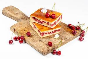 Cherry pie slices on a wooden kitchen Board with fresh cherries