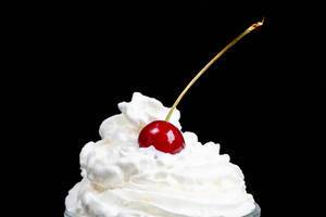 Cherry with whipped cream on a black background