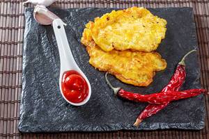 Chicken chops on a black stone tray with chili