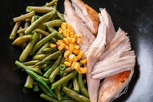 Chicken fillet with asparagus and corn on a black plate close-up